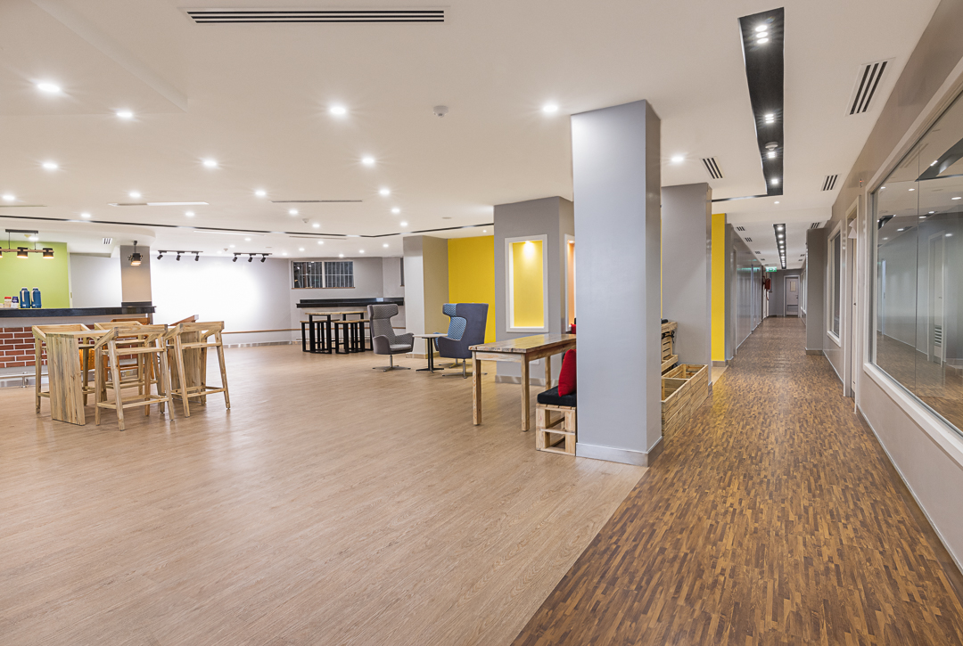 Open plan office area with different furniture organised in clusters, timber hardwood flooring and soft lighting in the Stanbic bank incubation centre designed by Arcs Africa