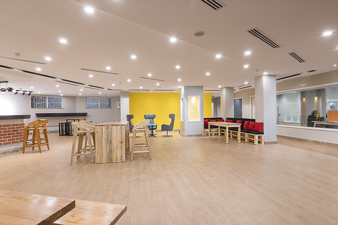 Open plan incubation area with different furniture organised in clusters, timber hardwood flooring and soft lighting in the Stanbic bank incubation centre designed by Arcs Africa