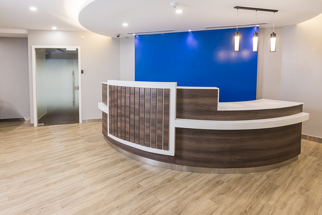 Modern reception area to Stanbic bank with a blue feature wall to reflect their brand colours and mahogany desk