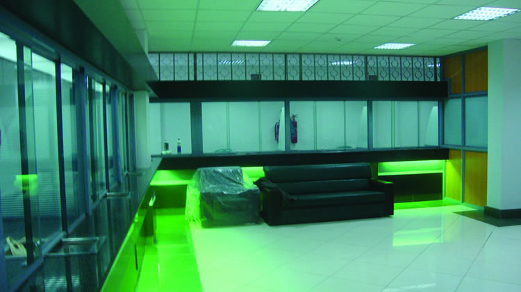 Interior of Cooperative bank showing green ambient lighting and black sofas in a banking hall