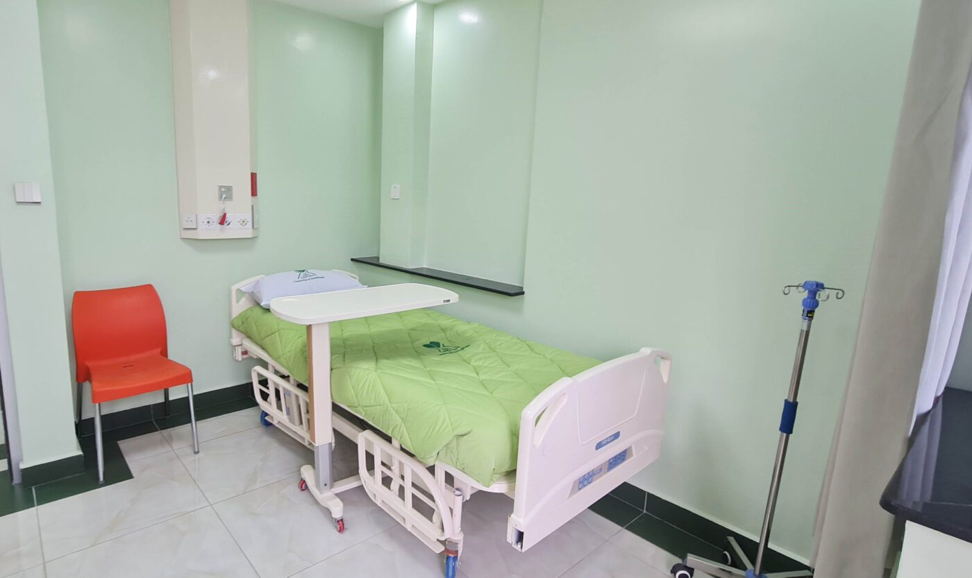 The interior of Karen Hospital patient suite, showing a bed and bedside table